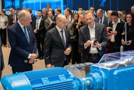 German Chancellor Olaf Scholz (center) and Lower Saxony's Prime Minister Stephan Weil (left) look at the Flender app on the smartphone ofFlender CEO Andreas Evertz. Digital intelligence makes the transmission transparent and delivers live data and recommendations for action directly to the app.